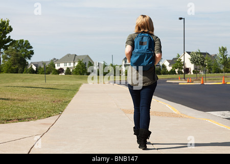 Female high school student walking along pavement Stock Photo