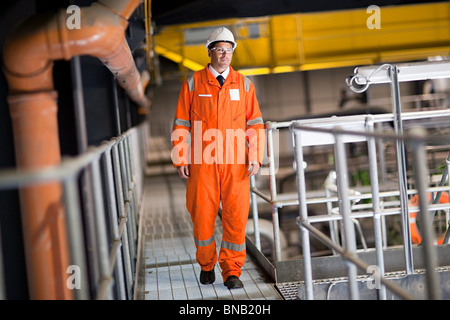 Engineer walking along walkway in factory Stock Photo