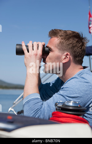 Man with binoculars on yacht Stock Photo
