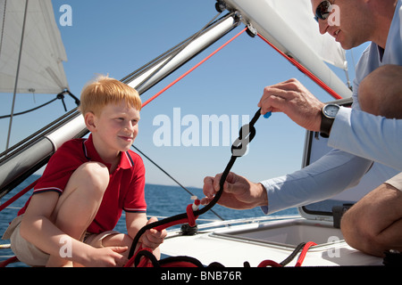 Man teaching boy knot on yacht Stock Photo