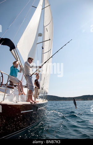 Father and sons fishing on yacht Stock Photo