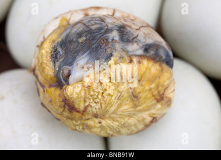 A balut, or cooked fertilized duck egg, removed from its shell is pictured among other whole balut eggs in the Philippines. Stock Photo