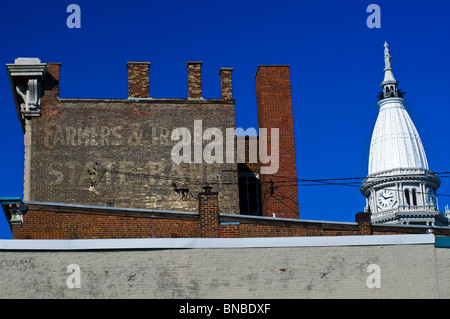 An old advertisement fades from a brick wall with the county courthouse in the background Stock Photo