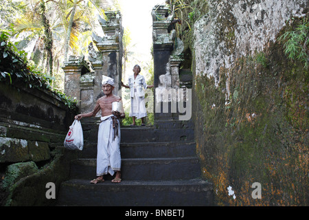 Elderly Balinese priest, and his wife, at the entrance to Yeh Pulu. Yeh Pulu relief is an ancient complex of rock carvings Stock Photo