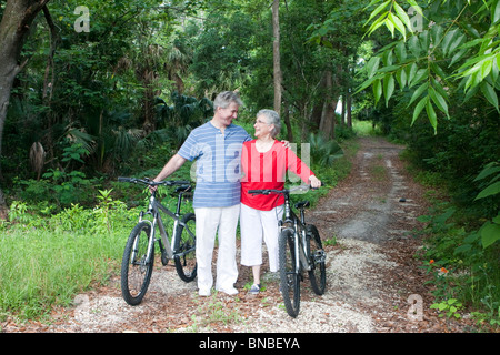 Senior couple walking bikes down a path Stock Photo