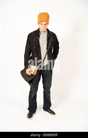 Pensive young man standing wearing beanie hat carrying book Stock Photo