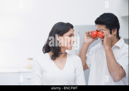 Couple making fun with tomatoes in the kitchen Stock Photo