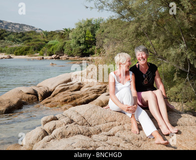 Two senior friends having a good time on the beach in Porto Cervo in Sardinia. Stock Photo