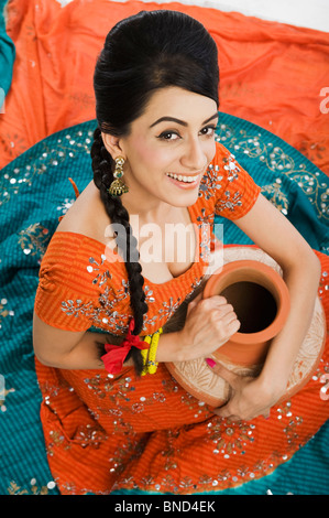 Woman in lehenga choli holding a clay water pot Stock Photo