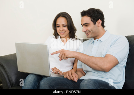 Couple using a laptop on a couch Stock Photo