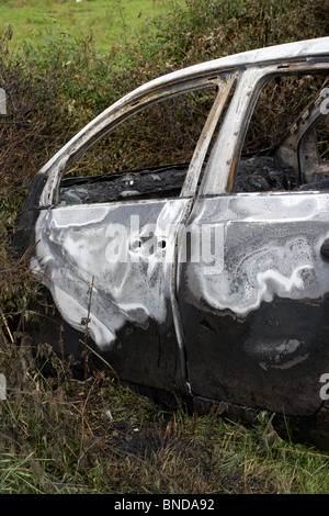 burned out stolen volkswagen golf car crashed into a ditch in northern ireland in the uk Stock Photo