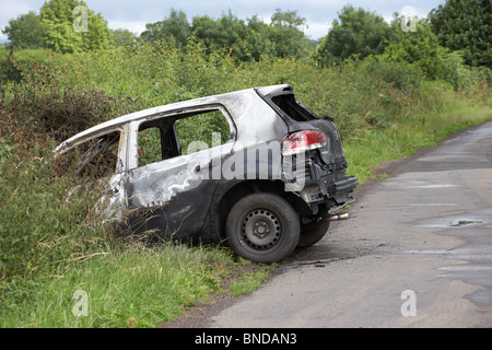 burned out stolen volkswagen golf car crashed into a ditch in northern ireland in the uk Stock Photo