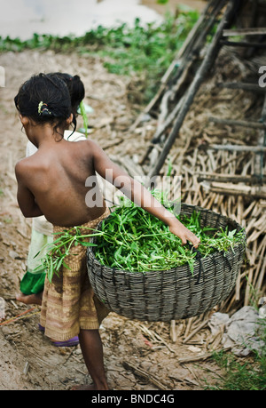 Two young khmer girls work and play by the water in a fishing village on the Tonle Sap near Siem Reap, Cambodia Stock Photo