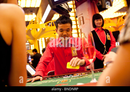 A croupier deals as models play Three Pictures at a table in the Ladies Club in the casino of Resorts World Sentosa in Singapore Stock Photo