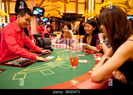 A croupier deals as models play Three Pictures at a table in the Ladies Club in the casino of Resorts World Sentosa in Singapore Stock Photo