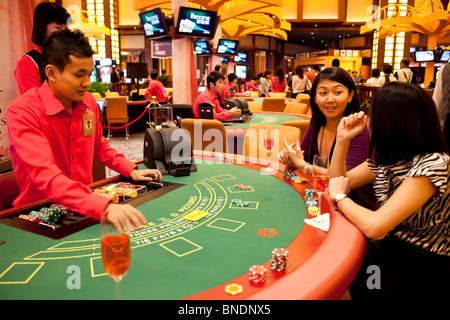 A croupier deals as models play Three Pictures at a table in the Ladies Club in the casino of Resorts World Sentosa in Singapore Stock Photo