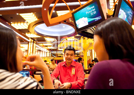 A croupier deals as models play Three Pictures at a table in the Ladies Club in the casino of Resorts World Sentosa in Singapore Stock Photo