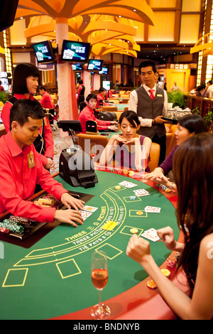 A croupier deals as models play Three Pictures at a table in the Ladies Club in the casino of Resorts World Sentosa in Singapore Stock Photo