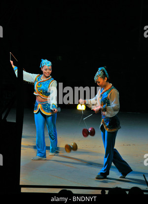 Chinese circus performers skillfully play with diabolos - Chinese wooden  spinning tops. Stock Photo