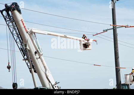 Construction workers in cherry picker baskets work on a new power transmission line. Stock Photo
