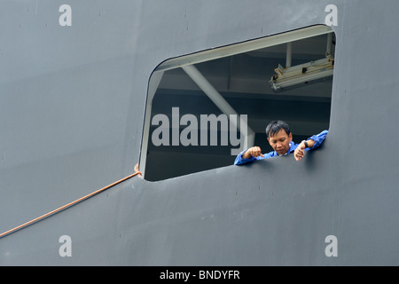 Ship worker looking through porthole, Durban Harbour, Durban, Kwazulu Natal, South Africa Stock Photo