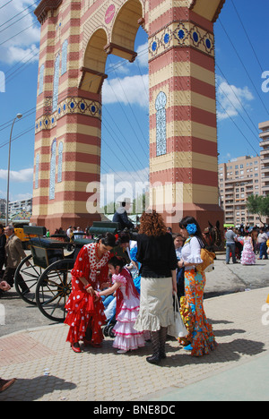 Women in flamenco dresses by the entrance to the feria ground, April spring fair, Seville, Seville Province, Andalucia, Spain. Stock Photo