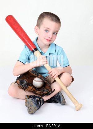 Preschool boy sitting down holding bat in studio Stock Photo
