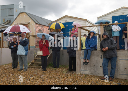 Group people watching event sheltering under umbrellas. Very wet stormy beach weather, summer rain UK. Whitstable Kent England. 2000s 2007 HOMER SYKES Stock Photo