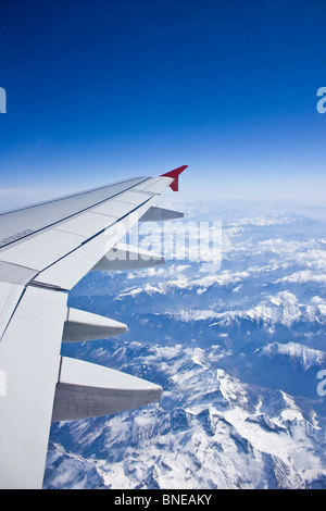 Flying over the alps, snow capped mountains, view of airplane wing Stock Photo