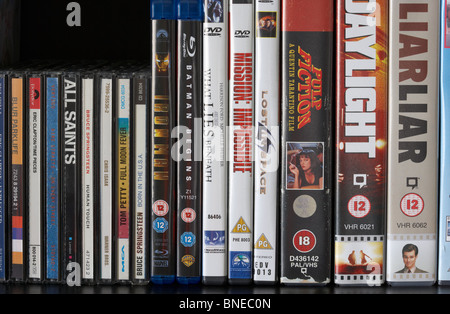 row of dvd vhs blu-ray video cases and cd albums on a shelf in the uk Stock Photo