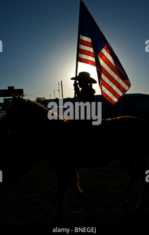 Cowgirl waving American flag at PRCA rodeo event in Texas, USA Stock Photo