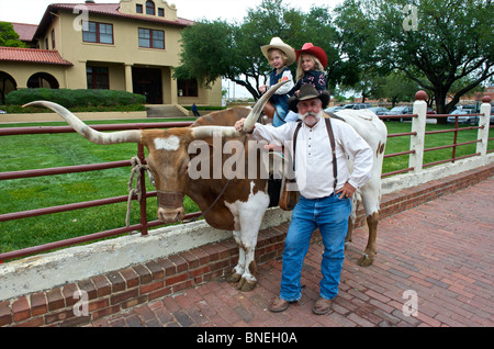 Children  on longhorns posing with grandfather in Fort Worth, Texas, USA Stock Photo