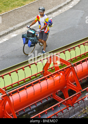 Touring cyclist waiting for combine harvester to pass - France. Stock Photo