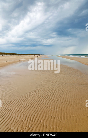 Sandy beach with wave patterns and thunder clouds Stock Photo