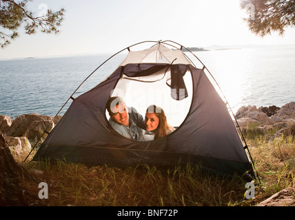 Couple lying in tent by sea Stock Photo