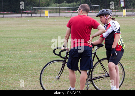 Young female racing cyclist with a helper at a grass track meeting Stock Photo