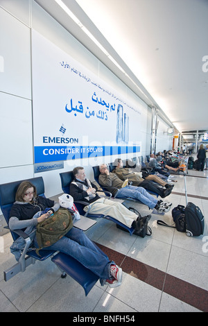 Travellers resting on reclining chairs at Dubai International Airport, Dubai, UAE. Stock Photo