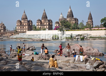 People bathing in the Petwa river. On the background the Royal cenotaphs. Orchha. India Stock Photo