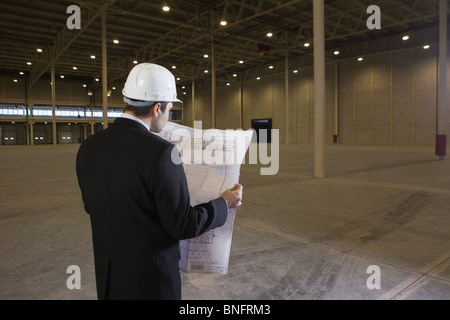 Man studies blueprint in empty warehouse Stock Photo