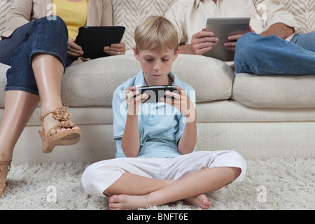Boy and parents sit with hand-held devices Stock Photo