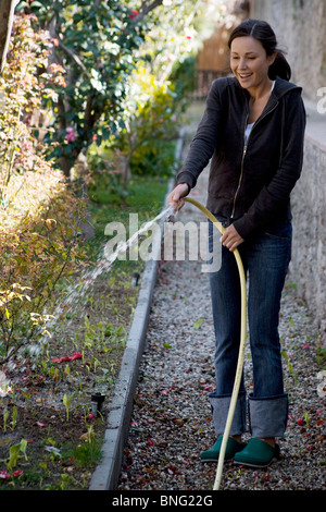 young woman watering with hosepipe Stock Photo