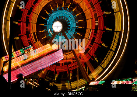 Amusement park rides spin and turn displaying bright colors on a summer night during Lakefair in Olympia, Washington. Stock Photo