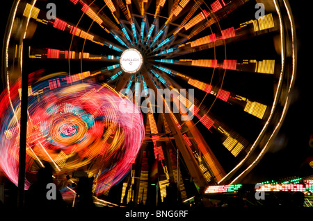 Amusement park rides spin and turn displaying bright colors on a summer night during Lakefair in Olympia, Washington. Stock Photo