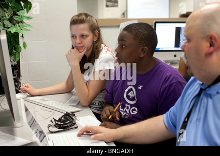 Geography teacher helps students doing internet-based research on computer in class at Manor New Tech High School in Manor Texas Stock Photo