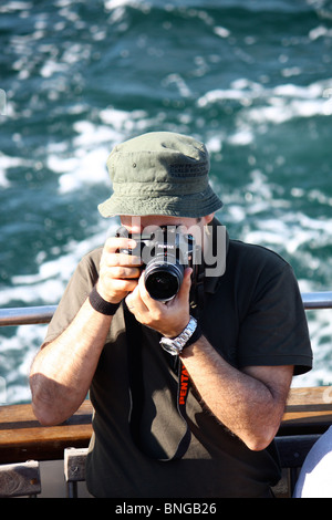 Photographer using a Pentax camera taking images during boat trip on holidays in the Azores Stock Photo
