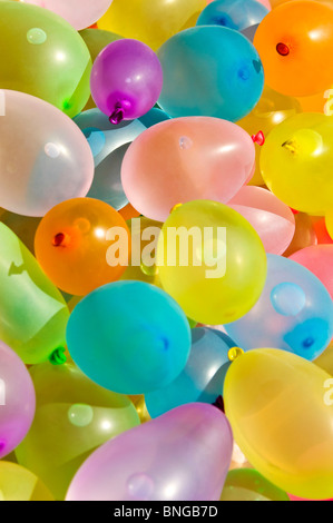 Vertical close up of hundreds of colourful latex balloons filled with water in preparation for a water fight. Stock Photo