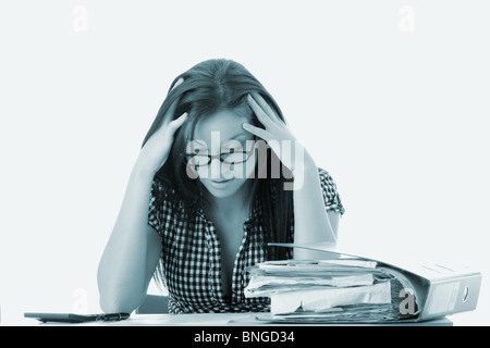 Tired female executive filling out tax forms while sitting at her desk. Stock Photo