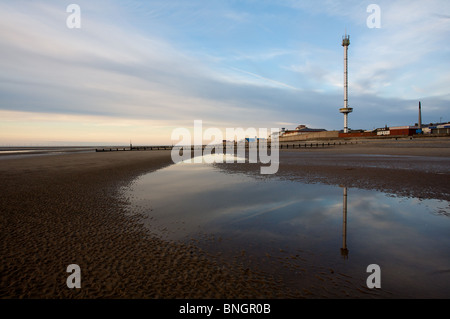 Rhyl sky tower is reflected in standing water on the beach at low tide towards sunset. Stock Photo