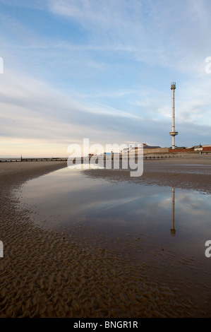 Rhyl sky tower is reflected in standing water on the beach at low tide nearing sunset. Stock Photo