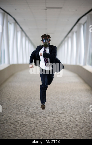 Businessman wearing gas mask running down corridor Stock Photo